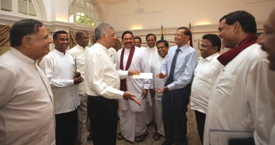 Frenemies? Opposition leader Ranil WIckremasinghe (L) greets External Affairs Minister G.L.Peiris (R) as President Mahinda Rajapakse  and his brother Minister Basil Rajapakse including several other government stalwarts look on.  